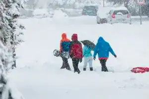 Nieve y personas con ropa de invierno caminando en una calle cubierta de nieve en un día de tormenta.