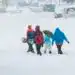 Nieve y personas con ropa de invierno caminando en una calle cubierta de nieve en un día de tormenta.