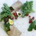 Frutas y verduras frescas, incluyendo aguacate, tomate, pimiento, kale y fresas, en una composición saludable para promover el bienestar y la alimentación natural.