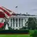 Bandera de Estados Unidos ondeando frente a la Casa Blanca en Washington, símbolo de poder y política americana, imagen representativa de inmigración y derechos en EE.UU. – SoyMigrante.com REVISTA