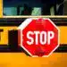 Parada de autobús con señal de stop en color rojo y fondo amarillo, importancia de seguridad vial y regulación en el transporte escolar.