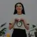 Reloj despertador en manos de joven mujer sonriente, concepto de gestión del tiempo y productividad en la comunidad migrante en España.