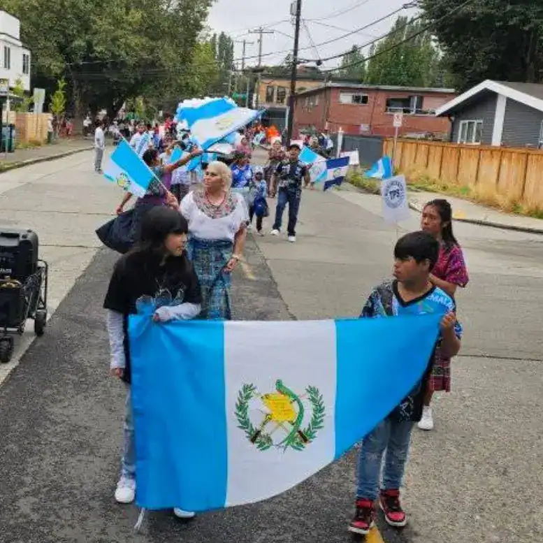 Guatemala bandera en celebración, comunidad migrante participando en evento cultural, reivindicación de identidad y raíces, niños y adultos mostrando orgullo nacional. – SoyMigrante.com REVISTA