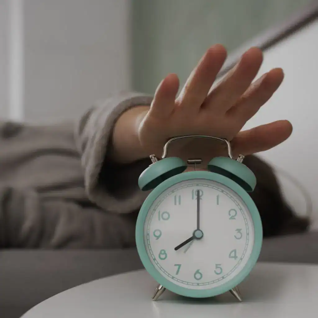Despertador mint verde, mano tocando una alarma, en un entorno de oficina o dormitorio, enfoque en reloj, concepto de tiempo y productividad para artículos de inmigración y migrante.