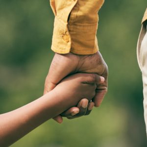 Manos entrelazadas de diferentes generaciones, simbolizando unión y apoyo en la comunidad migrante.