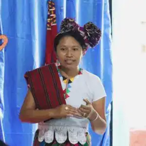 Reconocimiento de vestimenta tradicional indígena en México, mujer con tocado y vestimenta colorida.