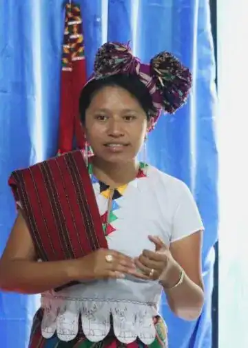 sakapulteko – SoyMigrante.com REVISTA Reconocimiento de vestimenta tradicional indígena en México, mujer con tocado y vestimenta colorida. – SoyMigrante.com REVISTA