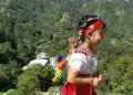 Niña indígena en trajes tradicionales con música y naturaleza en un paisaje montañoso. – SoyMigrante.com REVISTA