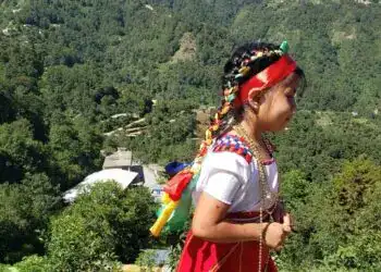 Fotografía Academia de Lenguas Mayas de Guatemala – SoyMigrante.com REVISTA Niña indígena en trajes tradicionales con música y naturaleza en un paisaje montañoso. – SoyMigrante.com REVISTA