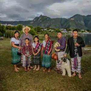 Gente indígena con trajes tradicionales y paisaje montañoso al fondo, reflejando cultura y tradición en México.