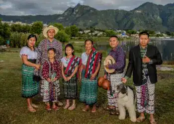 Gente indígena con trajes tradicionales y paisaje montañoso al fondo, reflejando cultura y tradición en México. – SoyMigrante.com REVISTA