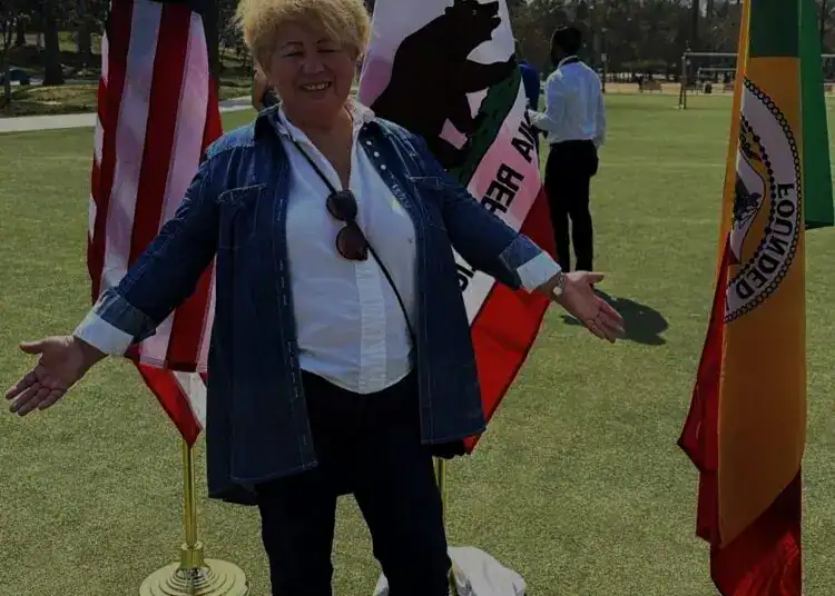Bandera de Estados Unidos, bandera de California, bandera de Alemania, mujer sonriendo en evento cultural internacional, diversidad y comunidad global. – SoyMigrante.com REVISTA