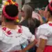 Vestido tradicional mexicano con bordados coloridos, celebra cultura y raíces en evento cultural en México. Mujeres con trajes típicos en celebración folklórica, mostrando identidad cultural y orgullo regional.