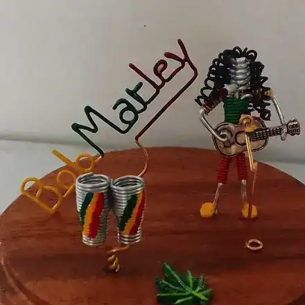 Creador de arte con latas recicladas de colores y musicalina que forma a un personaje con guitarra y nombre Marely, promoviendo la creatividad y el reciclaje en la comunidad migrante. – SoyMigrante.com REVISTA