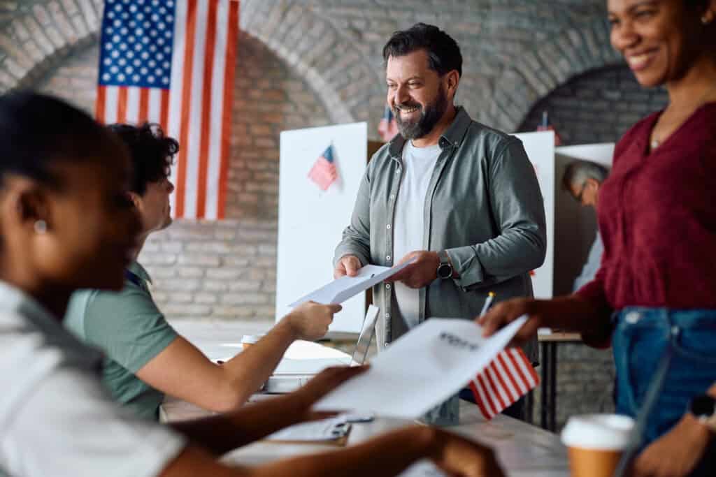 Happy mature man signing up to vote during US elections – SoyMigrante.com REVISTA Amigos migrantes participando en un proceso electoral en Estados Unidos, promoviendo derechos y participación de la comunidad latina en la política estadounidense. – SoyMigrante.com REVISTA
