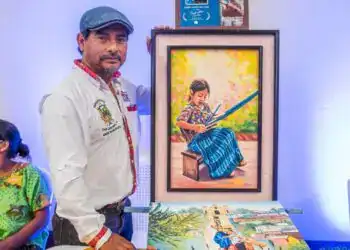 Colaborador mostrando su obra artística en una exposición de la revista SoyMigrante.com REVISTA en Guatemala. Destaca la cultura y el talento migrante a través del arte y la fotografía.