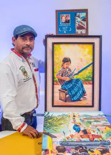Colaborador mostrando su obra artística en una exposición de la revista SoyMigrante.com REVISTA en Guatemala. Destaca la cultura y el talento migrante a través del arte y la fotografía. – SoyMigrante.com REVISTA