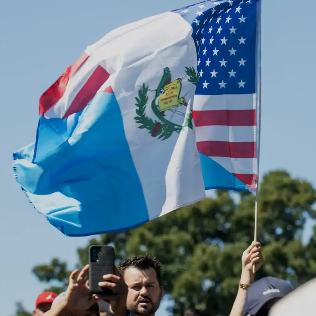 Bandera de Guatemala y Estados Unidos ondeadas en símbolo de migración y unión en evento público. – SoyMigrante.com REVISTA