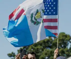 Bandera de Guatemala y Estados Unidos ondeadas en símbolo de migración y unión en evento público. – SoyMigrante.com REVISTA