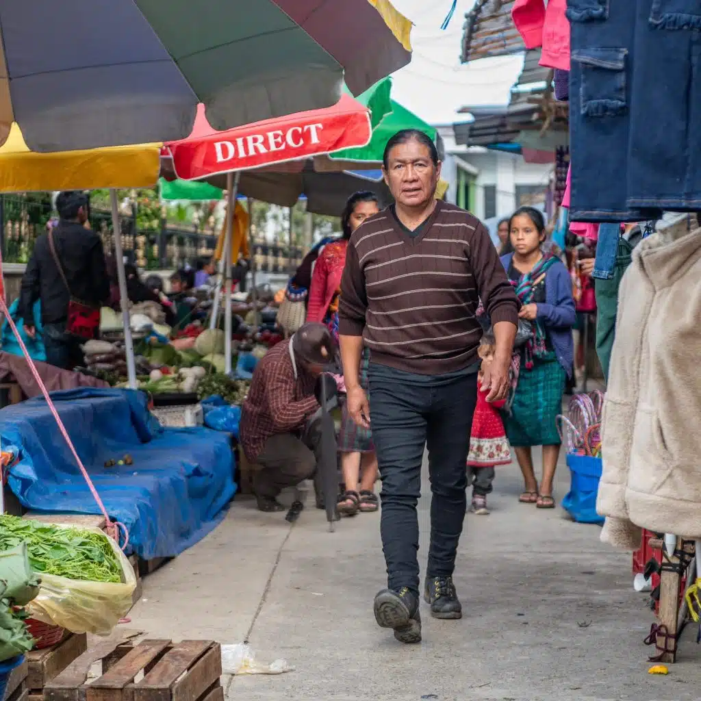 Vendedor ambulante en mercado al aire libre en una comunidad latinoamericana, promoviendo cooperación y cultura migrante en espacios públicos. – SoyMigrante.com REVISTA