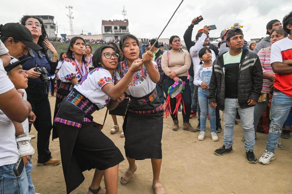 Personas indígenas participando en una ceremonia o evento cultural en una comunidad, mostrando tradiciones, vestimenta y expresión de identidad cultural en contexto de migración y comunidad. – SoyMigrante.com REVISTA