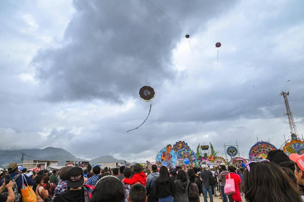 Colorido festival continuo en un campo abierto, con artistas, público y espectáculos culturales bajo un cielo nublado, refleja la vibrante celebración de la cultura y migración en la comunidad. – SoyMigrante.com REVISTA