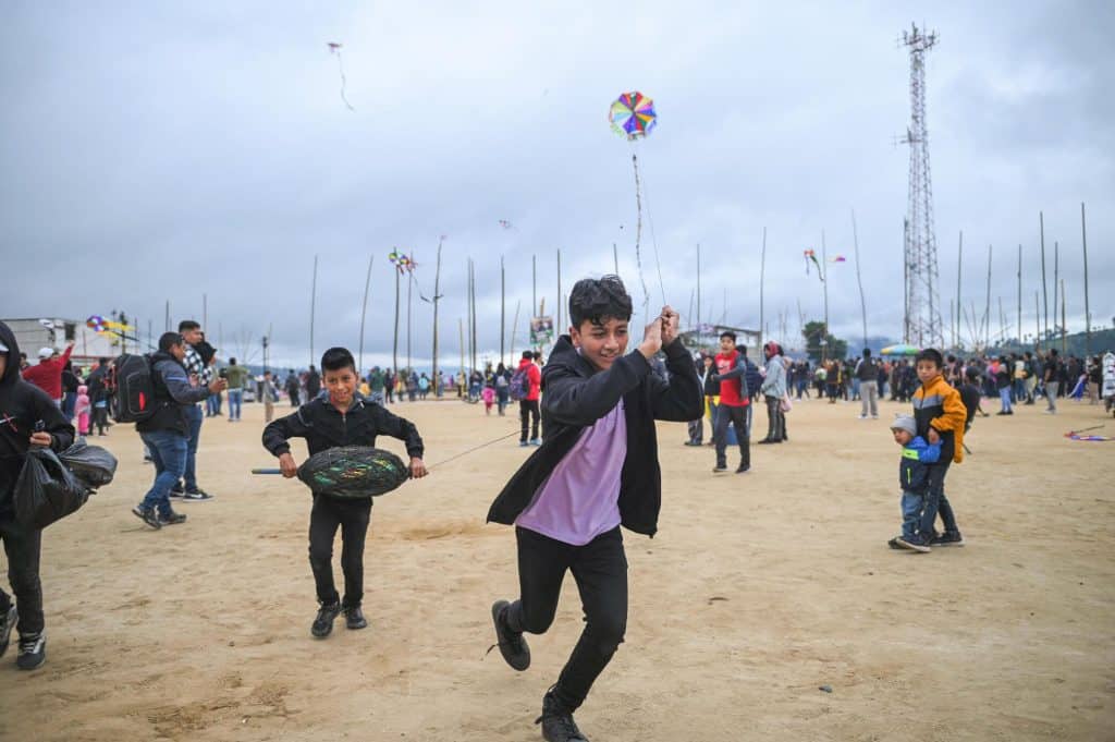 Viento y diversión en el festival de cometas para migrantes en México, niños disfrutando del aire y la cultura en un día familiar y festivo. – SoyMigrante.com REVISTA