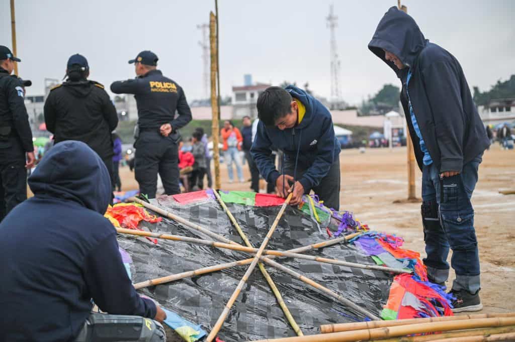 Niños migrantes construyen cometa en un campo de refugiados, reflejando esperanza y resiliencia en medio de la crisis migratoria en México. Fotografía que representa la lucha y la cultura de los migrantes. – SoyMigrante.com REVISTA