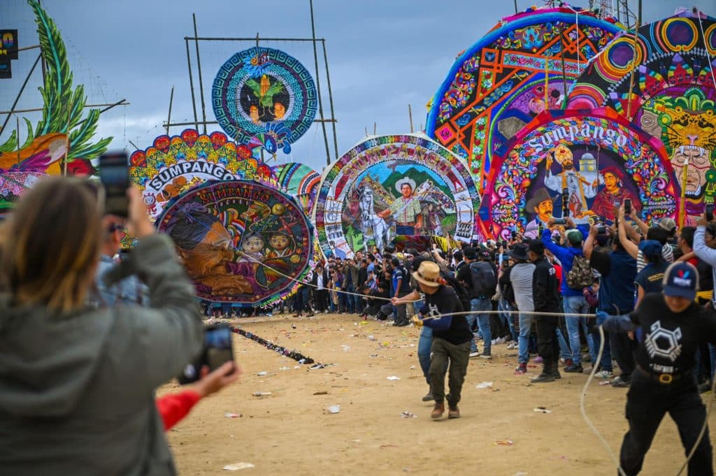 Colores y faroles tradicionales en el Festival Sumpango en Guatemala durante Día de los Muertos. Multitud disfrutando de la celebración con decoraciones vibrantes, cultura ancestral y actividades folklóricas. – SoyMigrante.com REVISTA