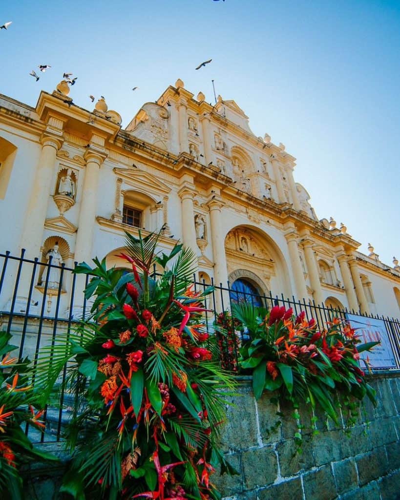 Catedral histórica con decoración floral vibrante en un día soleado, símbolo de cultura y patrimonio en Latinoamérica.