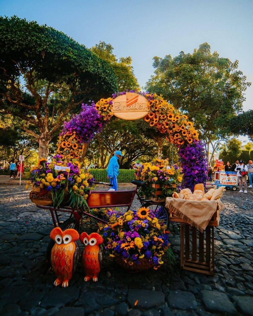 Arco floral en un mercado de flores en Guatemala, con flores coloridas, decoraciones tradicionales, y plantas típicas, reflejando cultura y tradiciones guatemaltecas.
