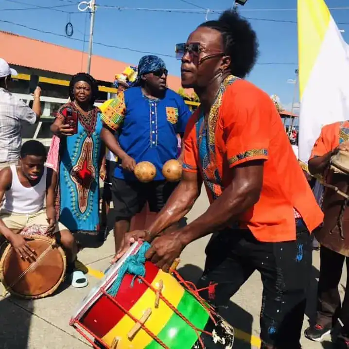 Vibrante celebración cultural con artistas tocando tambores y bailando en una festividad tradicional africana, destacando la música, el baile y las vestimentas coloridas. – SoyMigrante.com REVISTA