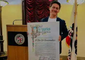Guatemalteco con resuelto en la ciudad de Los Ángeles, sosteniendo un cartel con la declaración oficial del "Día del Guatemalteco".