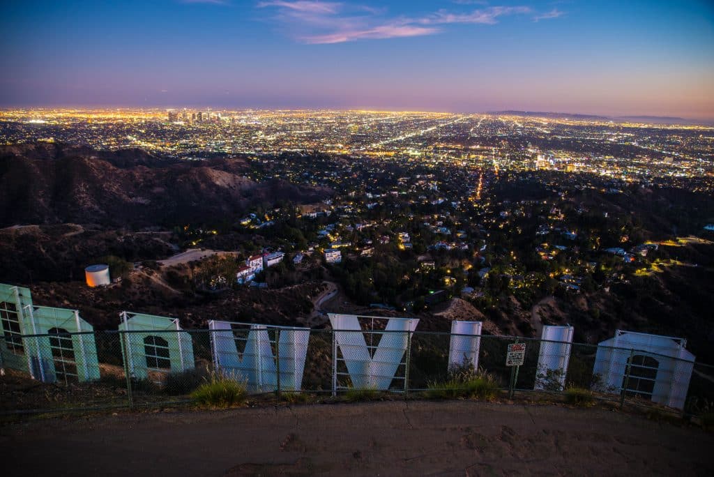 Vistas nocturnas de Los Ángeles desde Hollywood sign, ciudad iluminada, símbolo cultural y atractivo turístico en Estados Unidos.