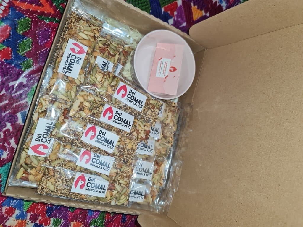 Gránola keto de del comal con semillas y frutos secos, ideal para una dieta saludable y baja en carbohidratos, presentada en caja con etiquetas y envuelta en plástico. – SoyMigrante.com REVISTA