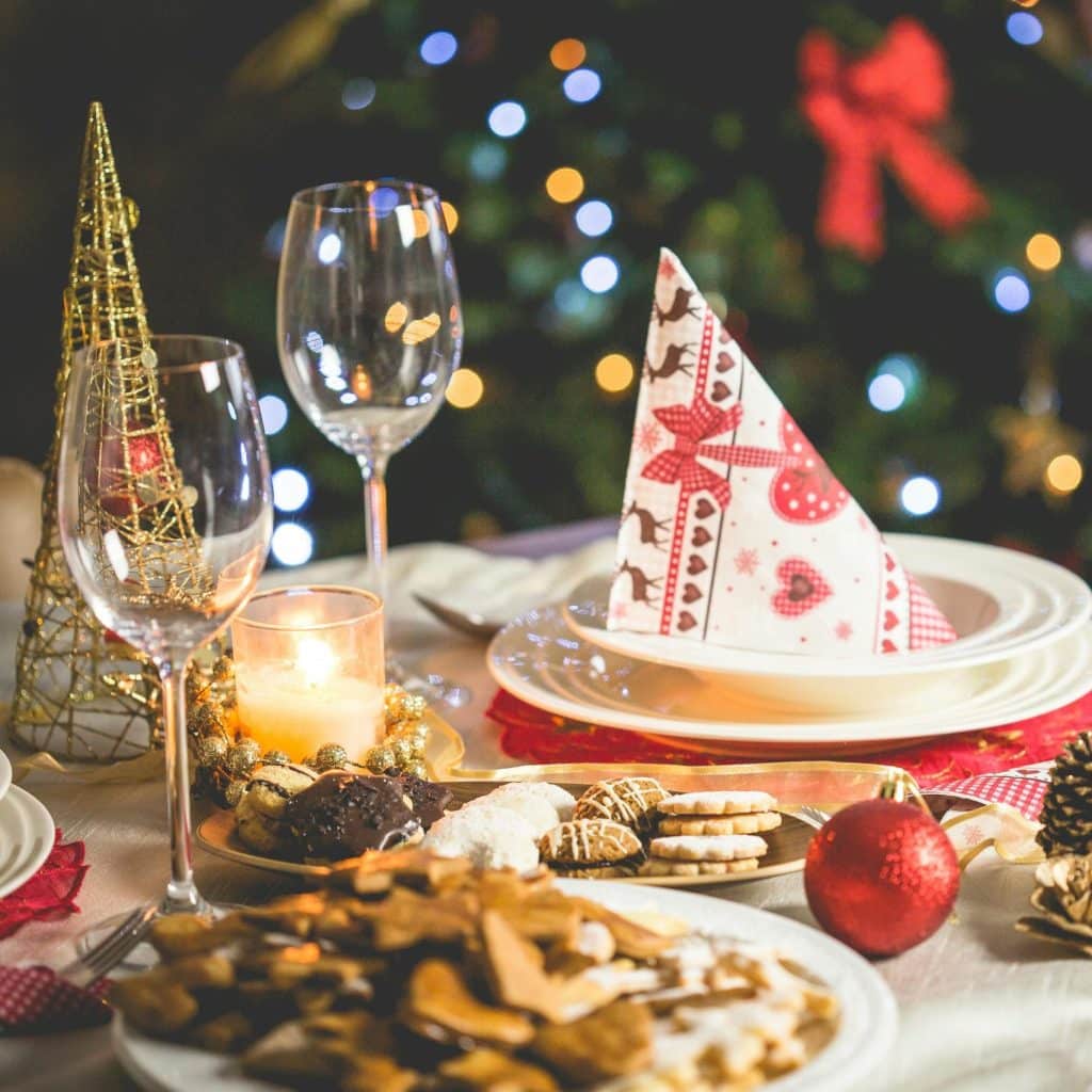 Decoración navideña con mesa festiva, galletas, copas de vino y un árbol de Navidad iluminado, ideal para celebrar y compartir en Navidad, con temática de festividades y tradiciones navideñas.