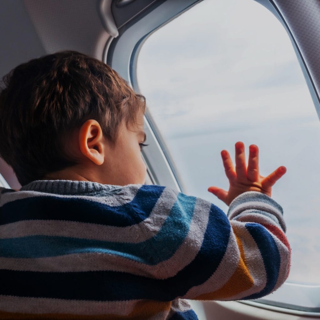 Niño mirando por la ventana de un avión, simbolizando viajes y migración, en el contexto de la revista SoyMigrante.com Revoluciona tus perspectivas sobre migración y cultura con contenido inspirador y relevante. – SoyMigrante.com REVISTA