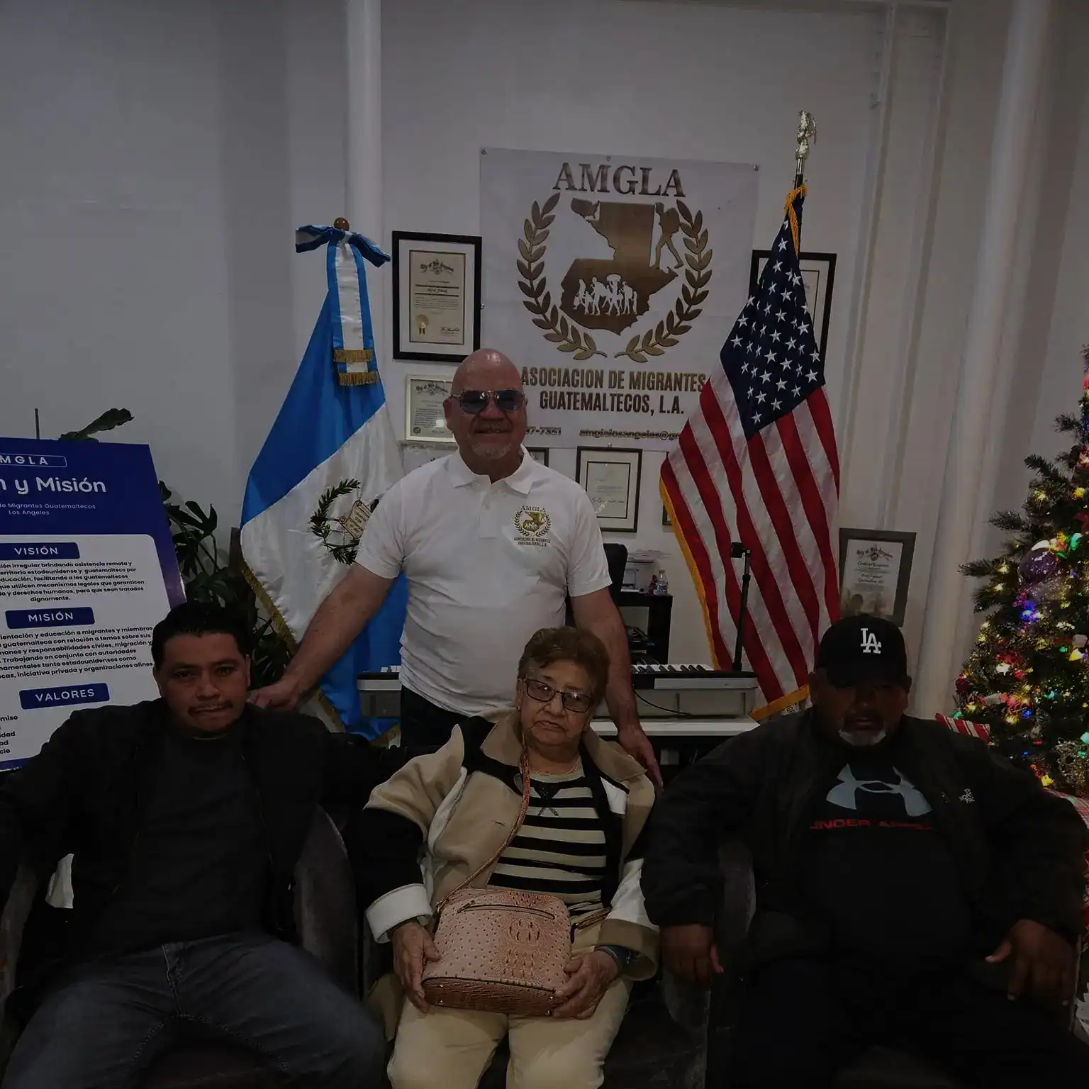 Asociación de migrantes guatemaltecos en Estados Unidos con membresía en AMGLA, mostrando liderazgo y comunidad migrante en el extranjero, con banderas de Guatemala y EE. UU. en fondo institucional.