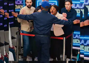 Persona en un enfrentamiento en un evento cultural, rodeada de jóvenes desconocidos, en un espacio con pantallas de neon que dicen "Black Friday". – SoyMigrante.com REVISTA