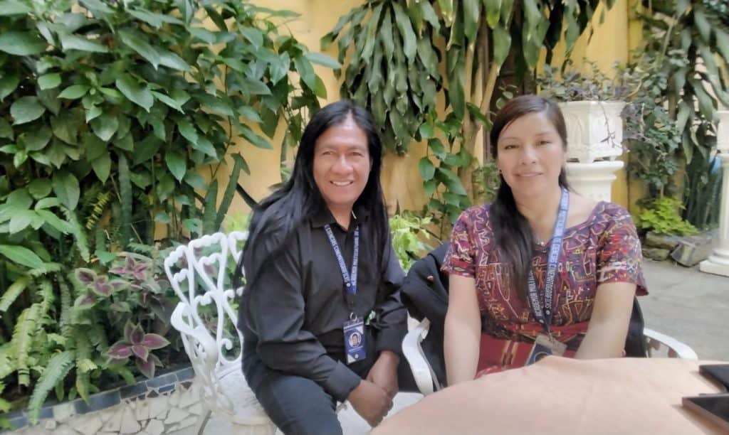 Migrantes en reunión, entrevista en Revista SoyMigrante.com, encuentro cultural y diálogo sobre migración y derechos humanos, paisaje con plantas verdes y ambiente cálido. – SoyMigrante.com REVISTA