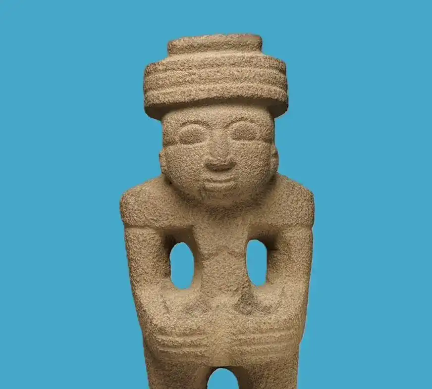 Arte prehispánico de Mesoamérica, escultura en piedra con figura humana y accesorios tradicionales, representando cultura indígena y tradiciones ancestrales en México. – SoyMigrante.com REVISTA