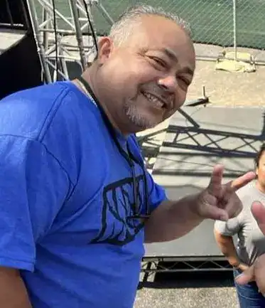 Hombre sonriendo en evento comunitario, participando en actividades culturales y sociales relacionadas con la migración en México. – SoyMigrante.com REVISTA