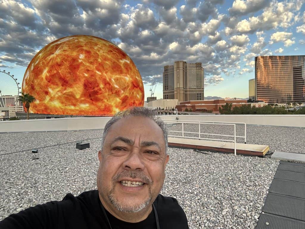 Sorpresa en Las Vegas con una gigantesca inversión de la NASA en un satélite en forma de sol, símbolo de energía y innovación, frente al Strip con modernos edificios y un cielo dramático. – SoyMigrante.com REVISTA