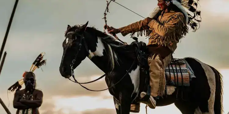 idiomas en estados unidos – SoyMigrante.com REVISTA Guerrero indígena montado a caballo con plumas tradicionales en ceremonia cultural en la naturaleza. – SoyMigrante.com REVISTA