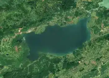 Lago rodeado de naturaleza verde y montañas, vista aérea, paisaje natural en una región tranquila y escénica.