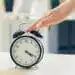 Reloj despertador clásico en una mesa, reloj despertador vintage para señal de tiempo, concepto de puntualidad y cultura laboral, relacionada con temas de migración y trabajo.