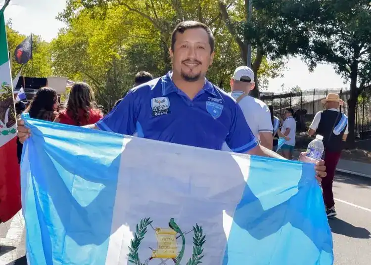 Guatemalteco con bandera en marcha patriótica, símbolo de orgullo y celebración nacional, participando en evento cultural y cívico.