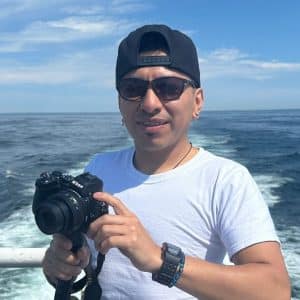 Nikon cámara fotográfica en manos de un hombre joven en barco en mar abierto durante el día.