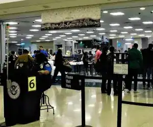 Pasajeros en el aeropuerto con personal de inmigración y control de seguridad, escenario común para migrantes en tránsito en una terminal aérea internacional.