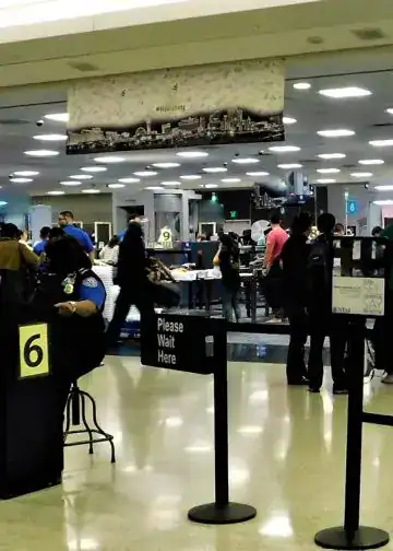 Pasajeros en el aeropuerto con personal de inmigración y control de seguridad, escenario común para migrantes en tránsito en una terminal aérea internacional. – SoyMigrante.com REVISTA